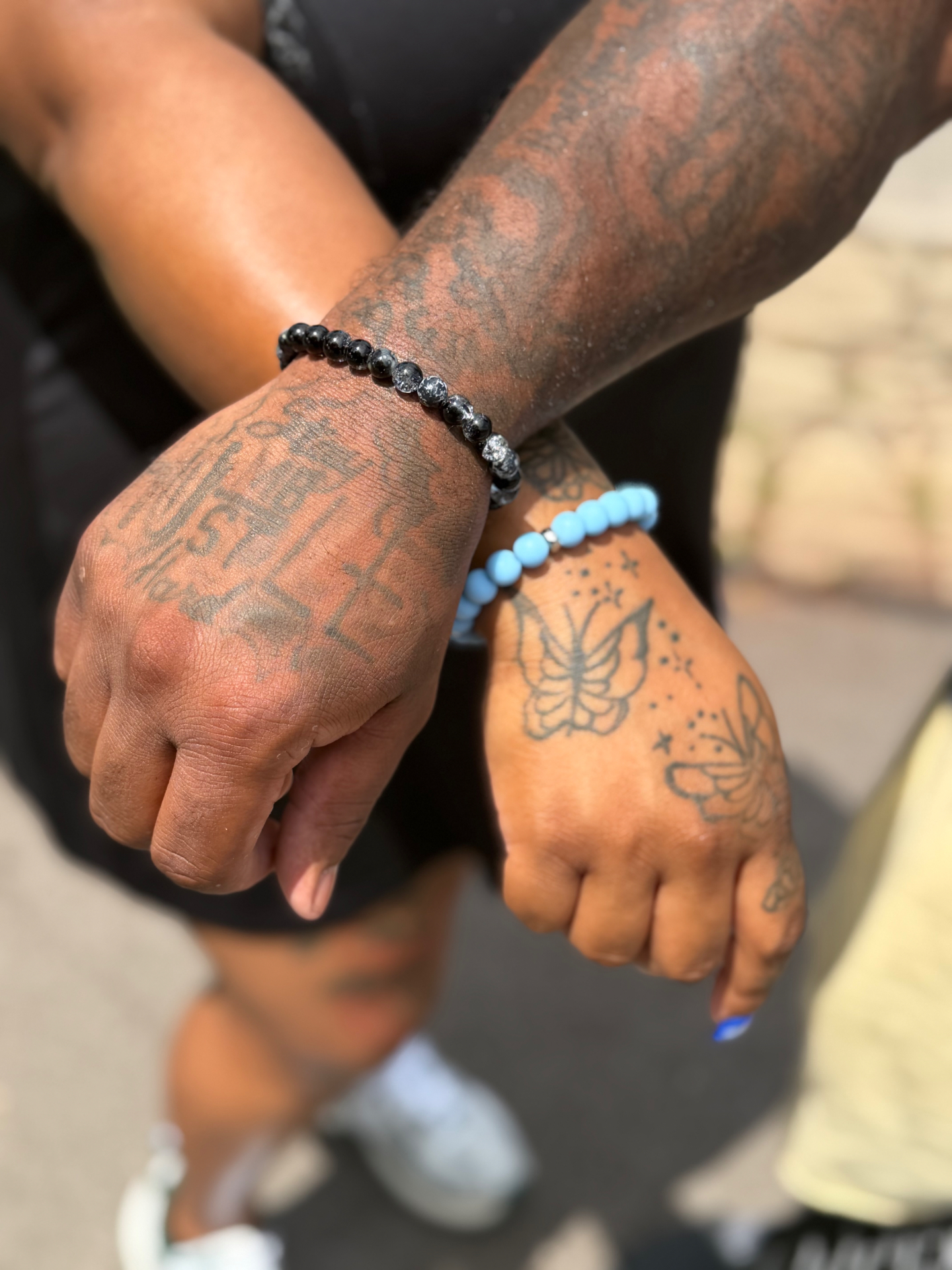 Two wrists side by side wearing matching handmade stillHER beaded bracelets
