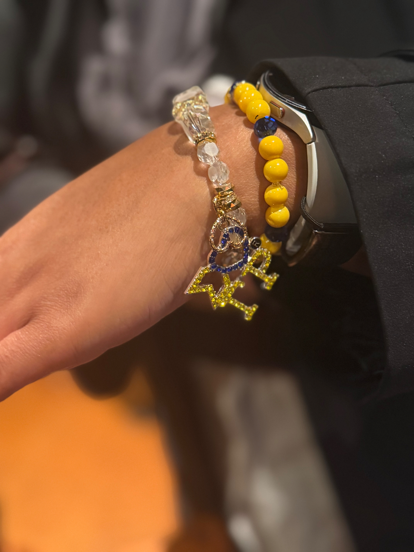 Charm bracelet stack with letter charms on a wrist
