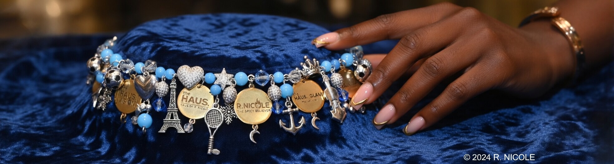 Charm bracelet resting on blue velvet, held by hand